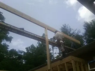 Carpenter setting a ridge beam over a new addition frame — Ice Dam Removal by Roofing Brothers in Barrytown