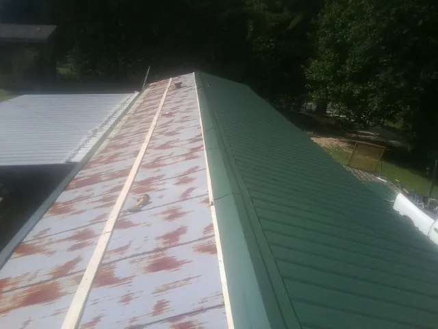 Old rusted panels beside newly installed green metal roofing — Wind Damage Roof Repair by Roofing Brothers in Barrytown