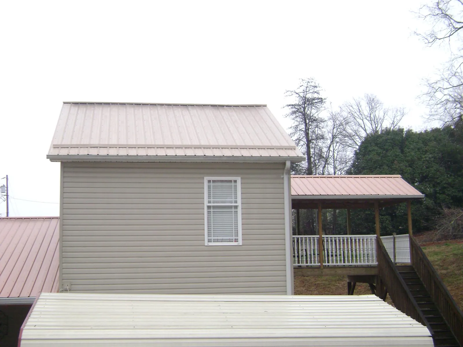 Tan metal roofs on a two story addition and attached porch, from a Roof Replacement job in Barrytown